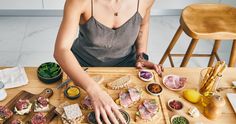 a woman sitting at a table with food on it and cutting up some meats