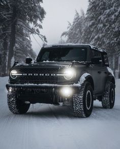 a truck driving down a snowy road with headlights on it's headlamps