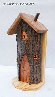 a tree stump with a small house on it's side and two windows in the front