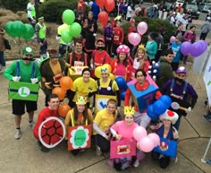 a group of people in costume posing for a photo with balloons and signs on their heads