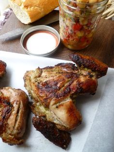 some food is laying out on a white plate next to a jar of sauce and bread