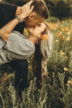 a man and woman kissing in the middle of a field full of yellow wildflowers