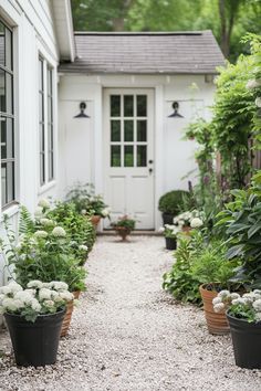 Backyard garden with a charming white door, featuring potted plants along a pea gravel path. Ideal for outdoor decor backyard and back garden ideas. White Pea Gravel Landscaping, Backyard Gardens Landscape, Gravel Area In Backyard, French Pea Gravel Garden, Pea Gravel Landscaping Flower Beds, Cottage Backyard Patio, Low Maintenance Cottage Garden, Gravel Backyard Landscaping, Landscape Ideas Low Maintenance