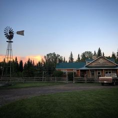 a truck parked in front of a farm house with a windmill on the other side