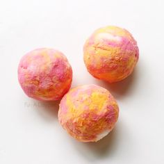 three pink and yellow balls on a white surface