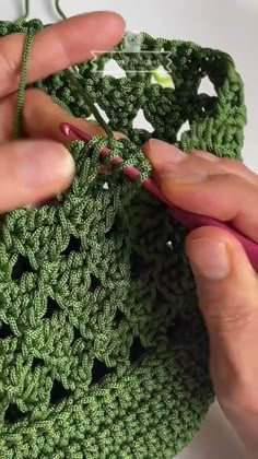 someone is crocheting on the edge of a green bag