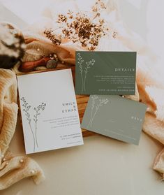 the wedding stationery is laid out on top of an unmade blanket and cloth