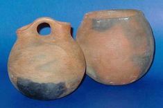 two clay vases sitting side by side on a blue background