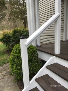 the steps leading up to a house with white railings and wood handrails