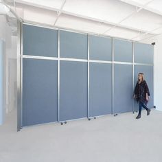 a woman standing in front of a wall with blue partitions on the sides and white walls behind her