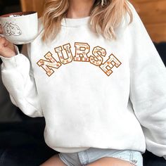 Cozy, Comfortable, and Career-Inspired Wrap yourself in warmth and style with our Nurse Fall Sweatshirt. Perfect for chilly shifts or relaxing days off, this sweatshirt is a must-have for any healthcare professional. Featuring a trendy, autumn-inspired "Nurse" text design, it's both comfortable and empowering. Comfort and Fit Versatile Style: Unisex fit for a comfortable, relaxed look. Cozy Fabric: Medium-heavy blend of 50% cotton and 50% polyester for warmth and softness. Classic Design: Crew neckline and classic fit for a clean, timeless style. Seamless Comfort: No itchy side seams for irritation-free wear. Durability Long-lasting Construction: Double-needle stitching at key seams for enhanced durability. Shape Retention: Ribbed knit collar maintains its shape after washing. Material and Nursing Long Sleeve Relaxed Fit Sweatshirt, Long Sleeve Nursing Sweatshirt With Relaxed Fit, White Long Sleeve Nursing T-shirt, White Relaxed Fit Sweatshirt For Nursing, Cotton Sweatshirt For Nursing In Fall, Fall Crew Neck Nursing Top, Fall Nursing Sweatshirt With Crew Neck, Cotton Nursing Sweatshirt For Fall, Nursing School Humor