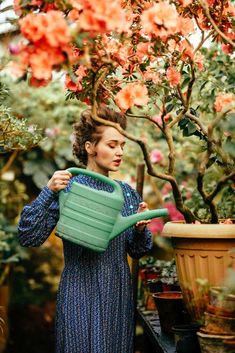 a woman holding a green watering can in her hands