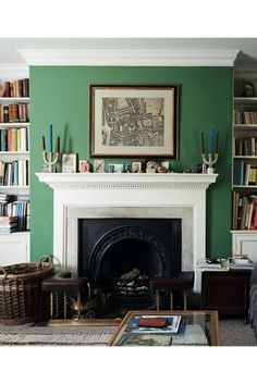 a living room filled with furniture and a fire place in front of a green wall