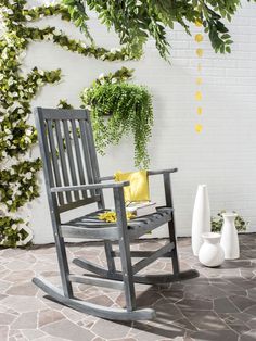 a wooden rocking chair sitting on top of a patio next to a potted plant