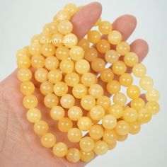 a hand is holding some yellow beads