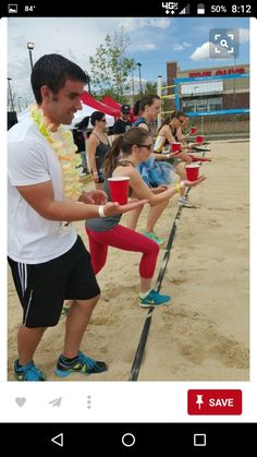 a group of people standing on top of a sandy beach holding red cups in their hands