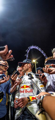 the man is signing autographs for his fans at the race track while he stands in front of him