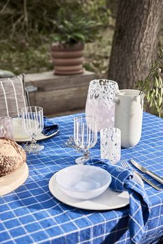 a blue table cloth with white plates and glasses on it