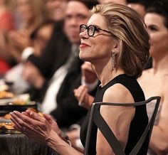 a woman in black dress sitting at a table with other people