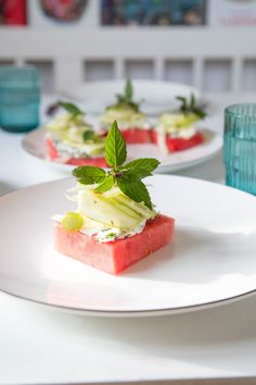 watermelon and cucumber dessert on a white plate with mint garnish