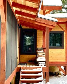 a cabin with snow on the ground and stairs leading up to it's front door