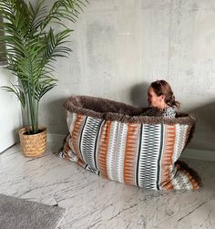 a woman sitting in a bean bag chair next to a potted plant on the floor