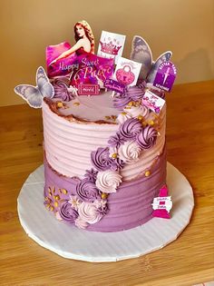 a birthday cake with purple frosting and cards on top, sitting on a wooden table