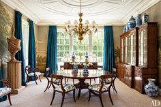 an elegant dining room with blue and white vases on the table in front of a large window