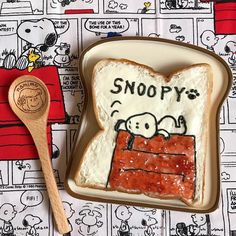 a peanut butter and jelly sandwich with snoopy written on it next to a spoon