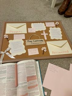 a bulletin board with some paper on top of it next to an open book and a pair of brown shoes