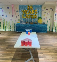 a table with cups on it in front of a sign that says 25 years later