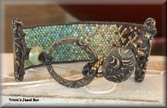 a close up of a metal object on a wooden table with beads and other items