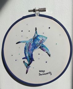 a blue and white dolphin painted on a wall hanging in front of a door with the words keep swimming