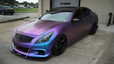 a purple and blue car parked in front of a garage