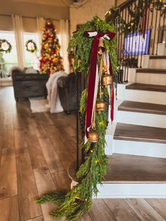 a christmas wreath with bells hanging from it's side on the bannister