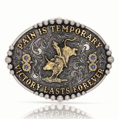 The Montana Silversmith Pain Is Temporary Attitude Belt Buckle is solid cast white metal alloy with a silver- and gold-toned finish. Antiqued with light engraving, the dark background contrasts nicely with the 2-toned design. A gold-toned bull and rider sit center, surrounded by the words "Pain is temporary" "Victory lasts forever" and 2 flowers on either side with center stones. Framed with silver-toned beading. Oval buckle with standard 1.5" belt swivel. Montana Armor protective finish to prev Pain Is Temporary, Figure Sitting, Cowboy Belt Buckles, Bull Rider, Nice Belts, Western Buckles, Bead Frame, Bull Riders, Western Belt Buckles