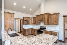 an empty kitchen with granite counter tops and wooden cabinets