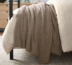 a bed with a blanket and pillows on top of it, next to a dresser