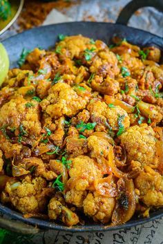 cauliflower and onions in a skillet with some garnish on the side