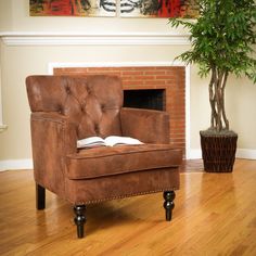 a brown chair sitting on top of a hard wood floor next to a potted plant