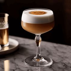 a glass filled with liquid sitting on top of a table next to another glass full of liquid