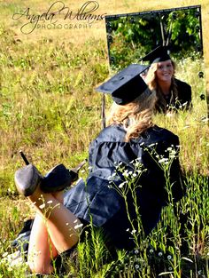 a woman sitting on the ground in front of a mirror wearing a graduation cap and gown