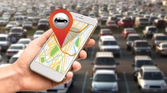 a person holding a cell phone in front of a parking lot filled with parked cars