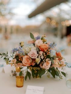 a vase filled with lots of flowers sitting on top of a table next to candles