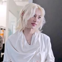 a woman with blonde hair is wearing a white shirt and looking off to the side