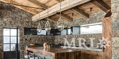 a rustic kitchen with stone walls and exposed beams is featured in this image, along with an island made out of wooden planks