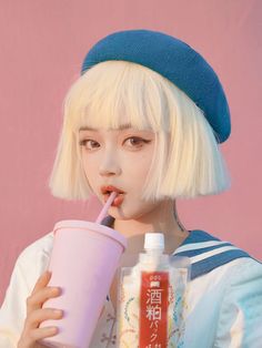 a woman with blonde hair drinking from a pink cup and holding a straw in her mouth