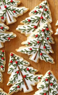 christmas cookies decorated with white icing and red berries are arranged on a wooden board