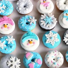 a box filled with frosted cupcakes covered in frosting and snowflakes