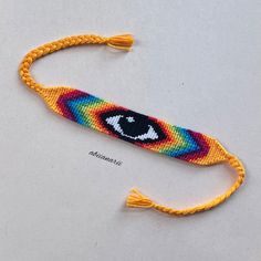 a piece of string art with an eye on it's end and a tassel